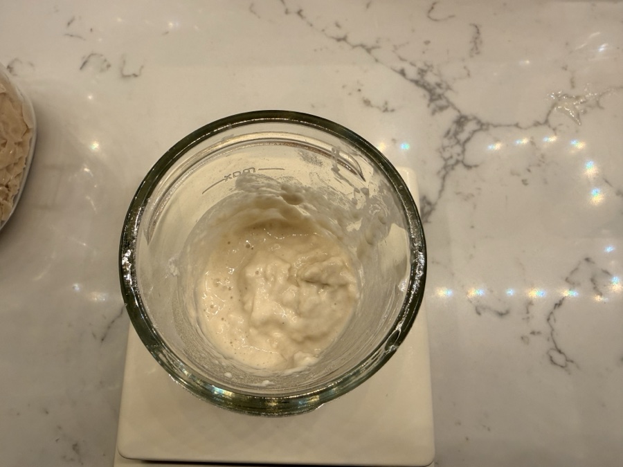 Dried sourdough starter flakes dissolved into a smooth paste, ready for flour to be stirred in