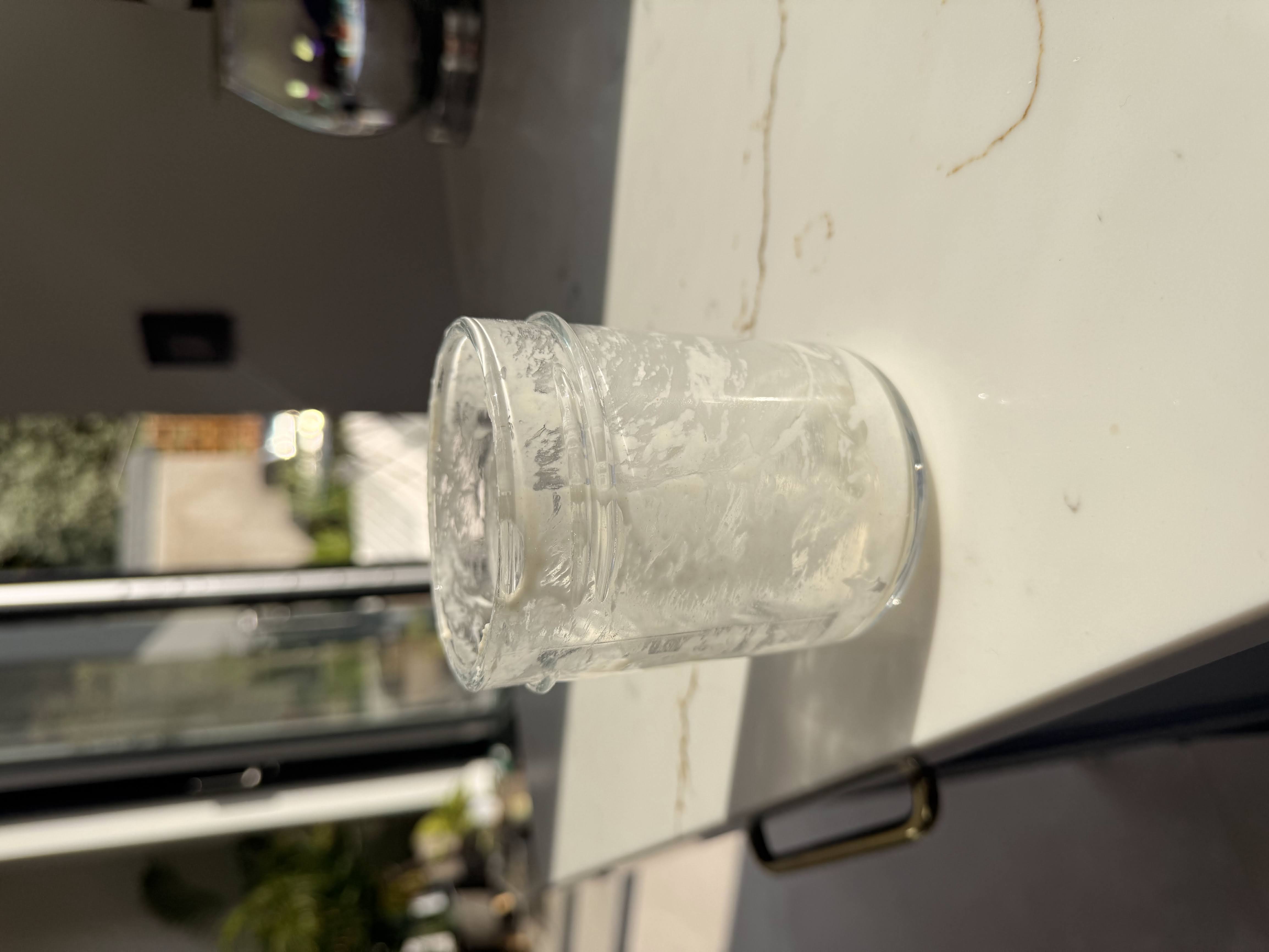 Glass jar showing small amount of sourdough starter scrapings at the bottom